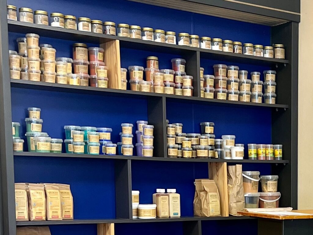 Regal mit Pflegemitteln und Naturfarben im Naturo Studio